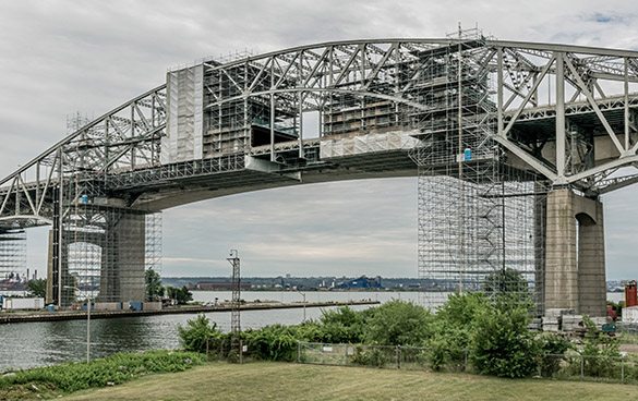 Metal arch bridge under construction. The bridge spans a river.