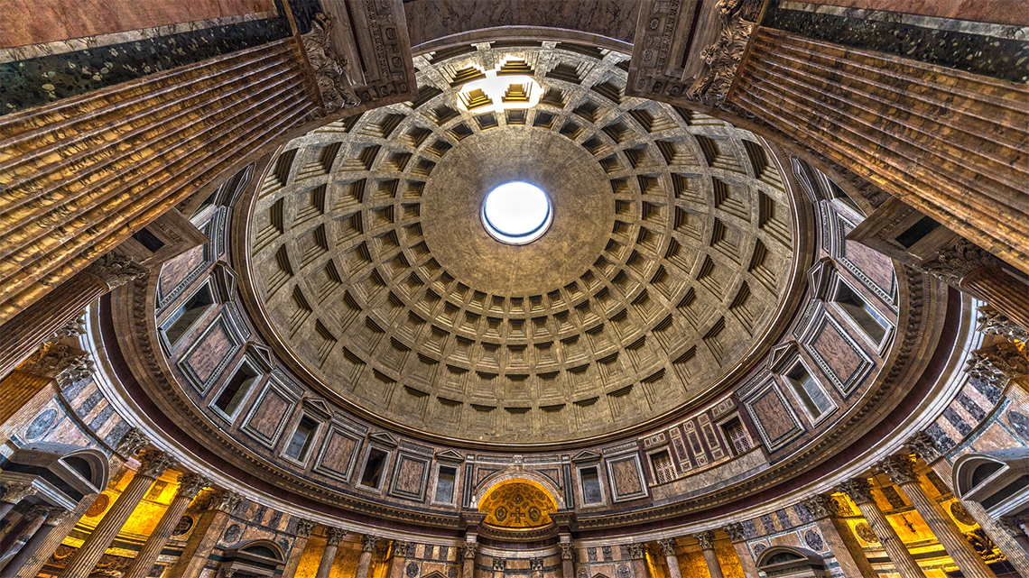 Dome roof of stone with a small opening in the middle. Circular and straight support pieces help hold up the roof.