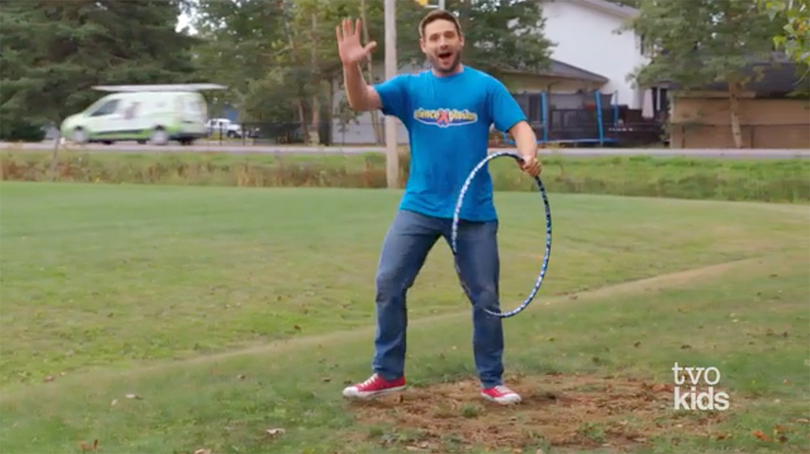 A person standing in a grassy field while holding a hula hoop.
