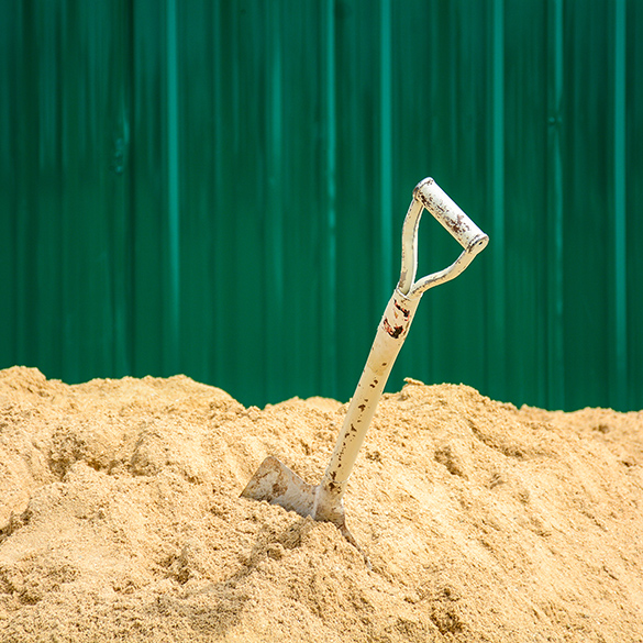 A shovel placed in a large pile of sand