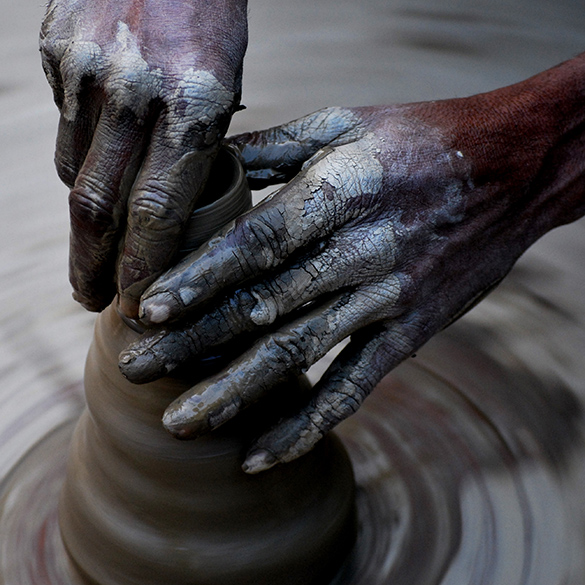 Hands molding and shaping clay into a structure