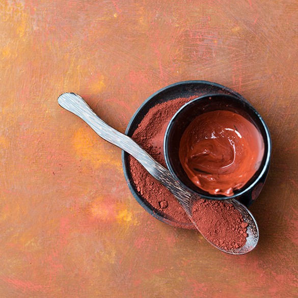 Red clay within a bowl on a plate with a spoon of clay