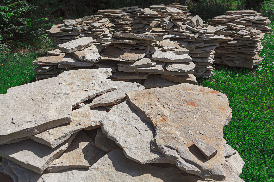 Slabs of rocks in different piles in a green space.