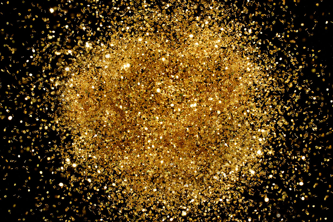 A small pile of shiny particles lies on top of black background.