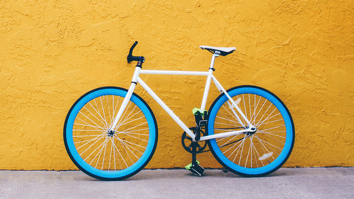 A fixed-gear bicycle rests against the wall of a building.