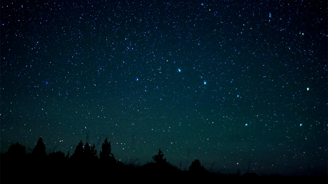 A night sky filled with stars. There is a grouping of stars that are known as the Big Dipper.