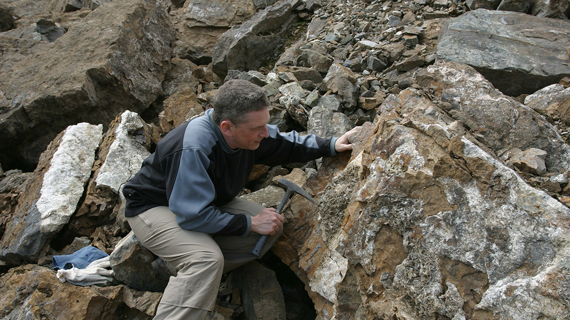 A geoscientist examining rock formations in a quarry.