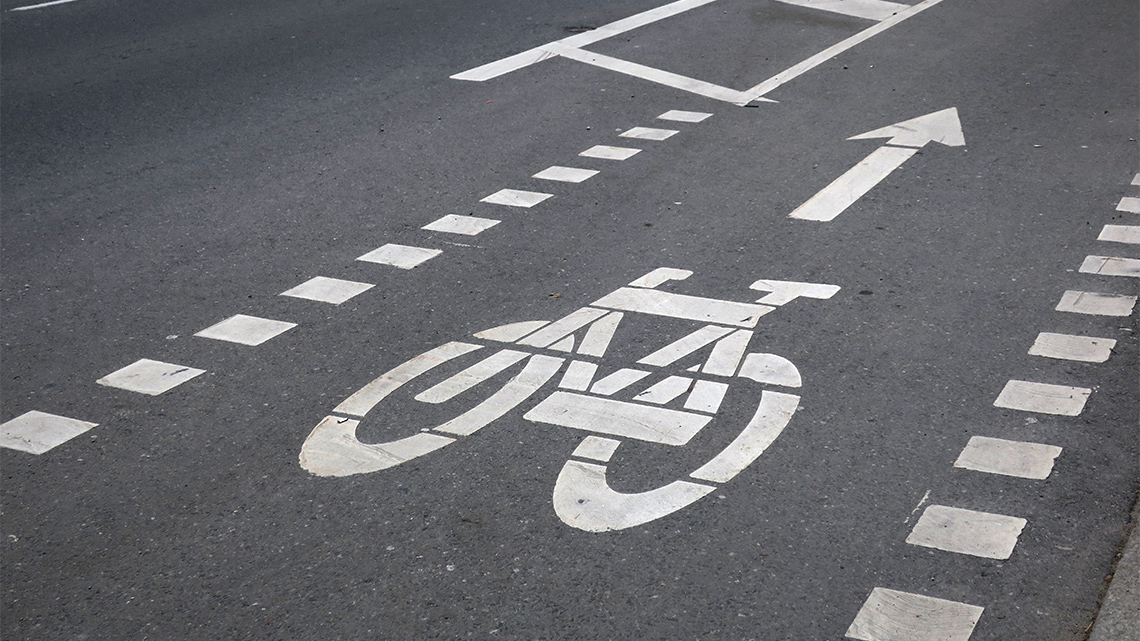 Bicycle icon and arrow showing the way forward in a bike lane on a city street.