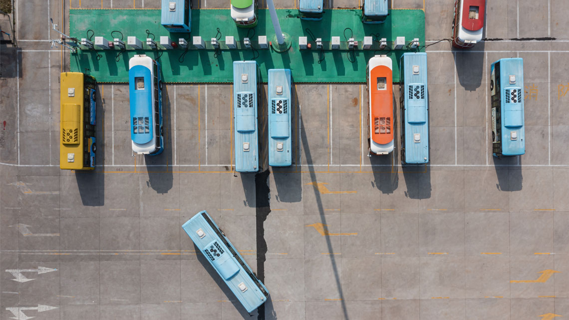 A row of buses charging at a bus terminal.