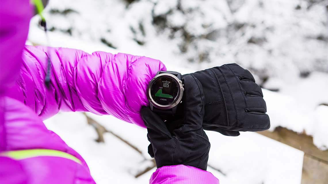 A person checks their smart watch outside on winter’s day.