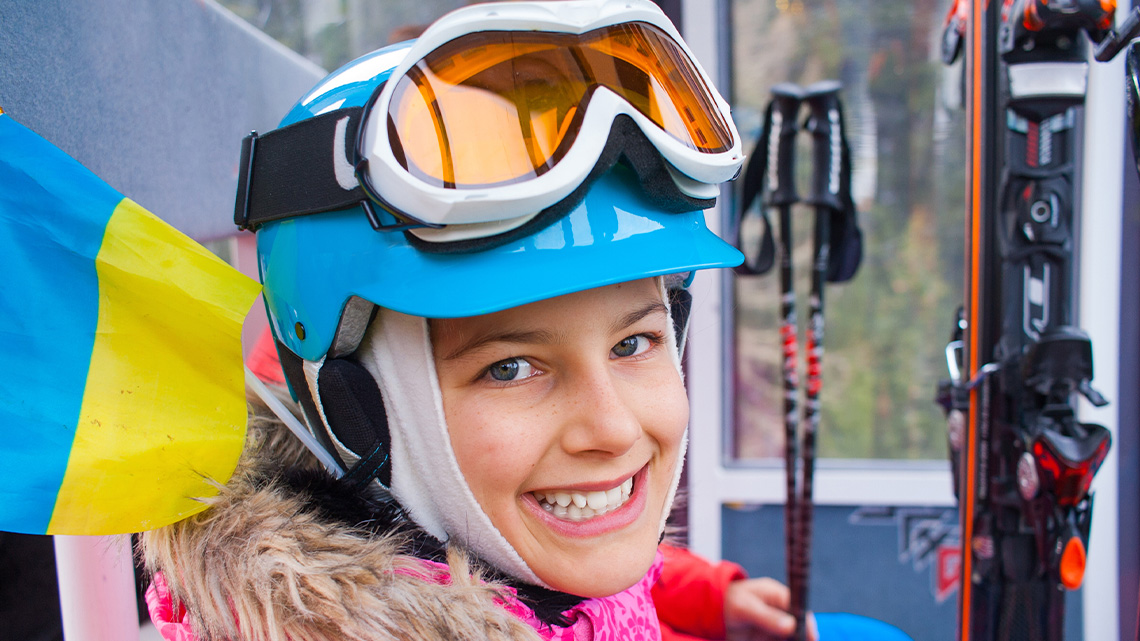 A ski helmet with curved padded parts to cover the ears and goggles attached at the top.