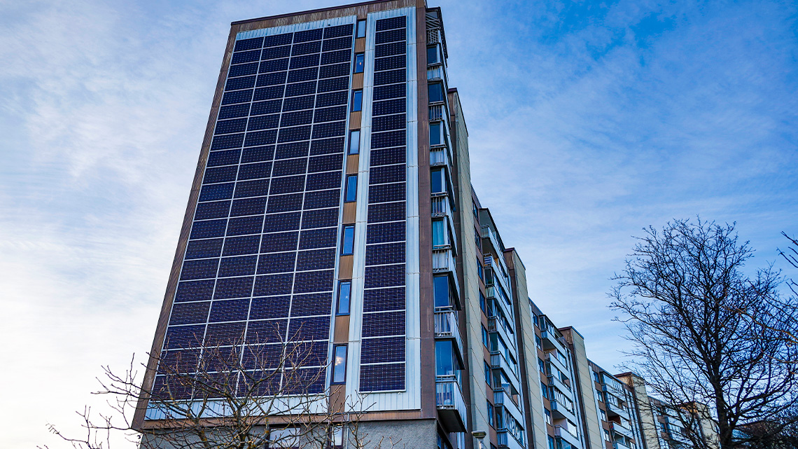 An apartment with solar panels on the side of the building from top to bottom between balconies.