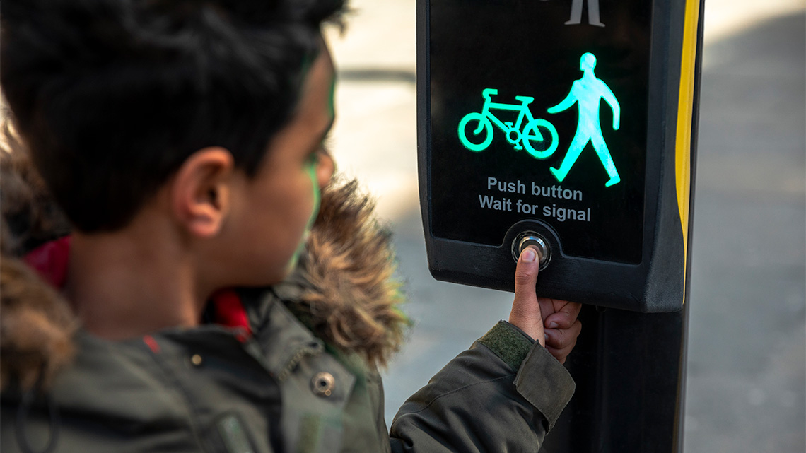 A person pressing the walk button at an intersection. 