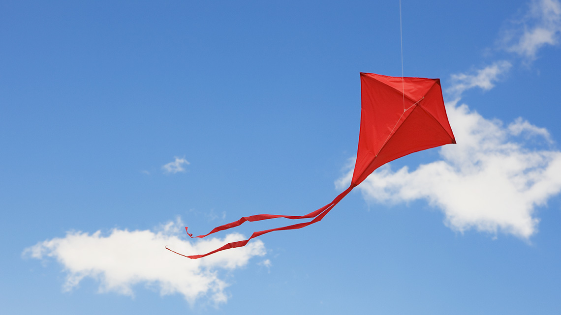 A colourful kite flying away in the sky.