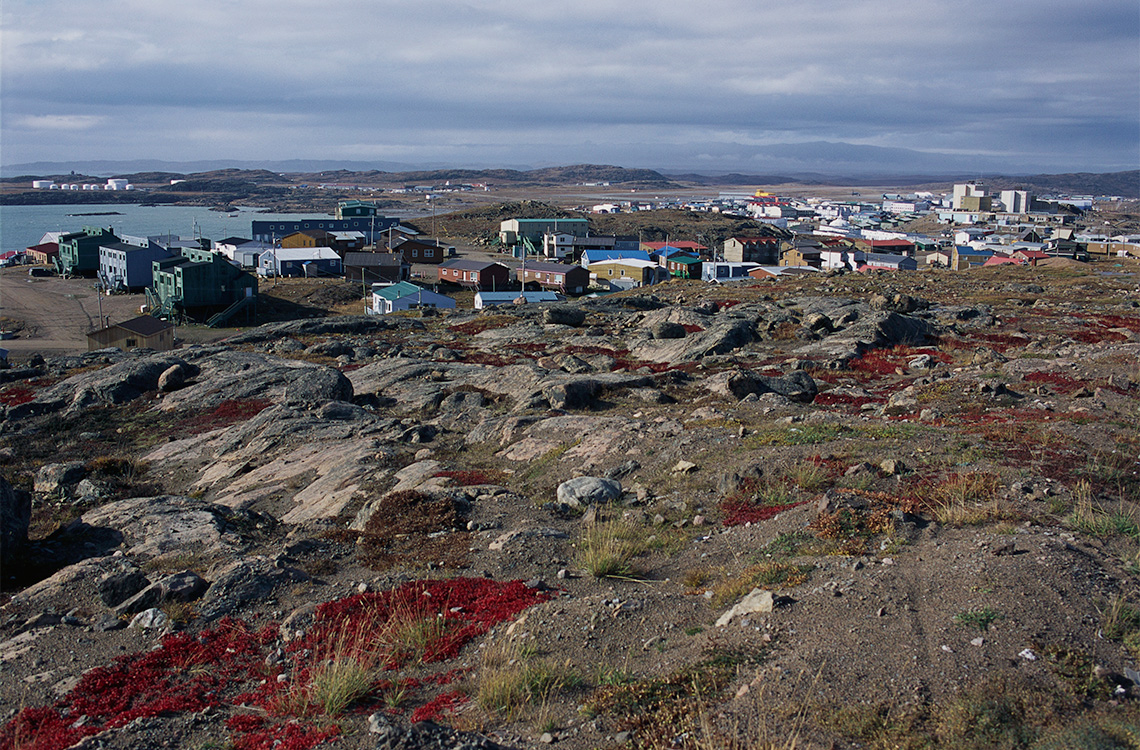 Sparse, hilly, rocky ground with colourful houses in the distance in Iqaluit, Nunavut.