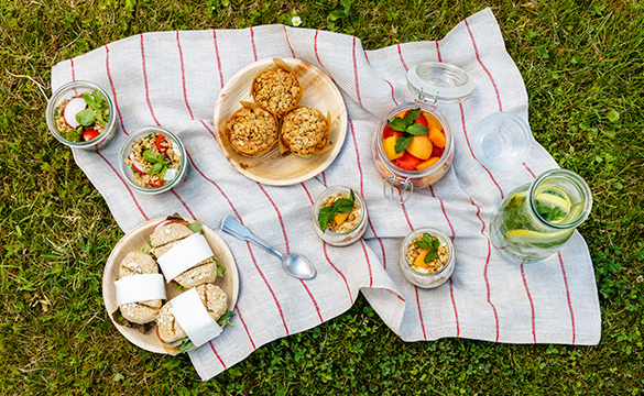 A blanket on the grass with different food on top.