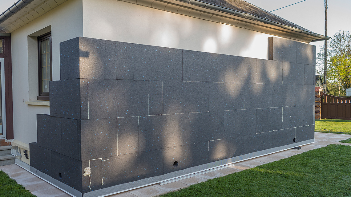 A one-storey building partially covered with rectangular blocks of polyurethane foam. 