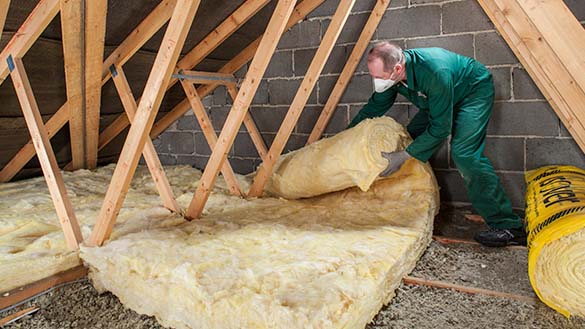 A person wearing a mask, gloves and a jumpsuit as they install insulation.