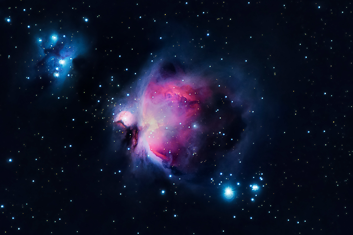 The Orion nebula. Clouds of coloured gas against a backdrop of stars of different sizes and brightness.