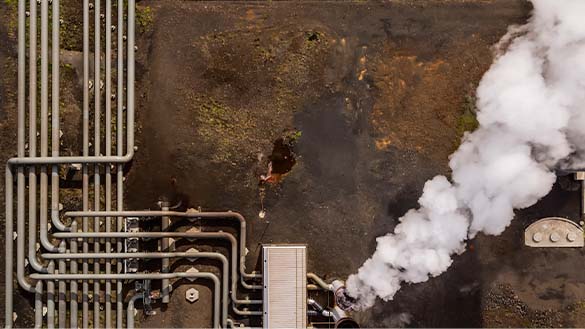 A wall covered in pipes producing steam.