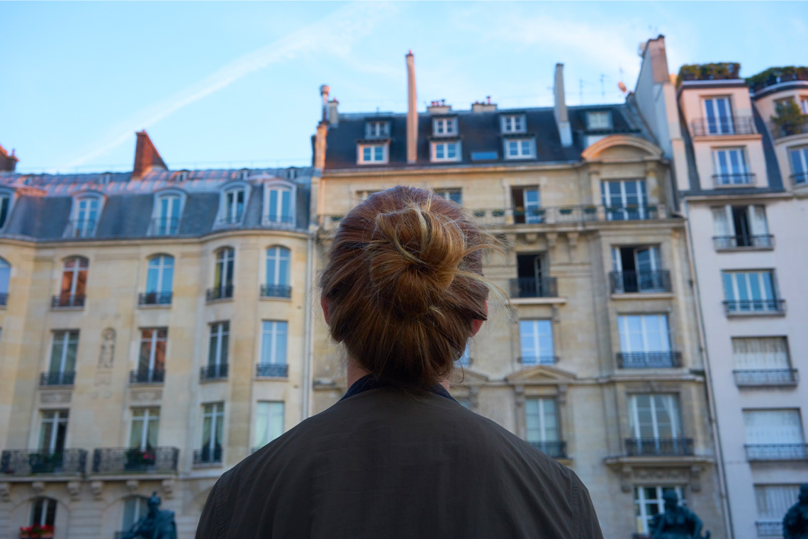 A person standing with tall glass buildings around them.