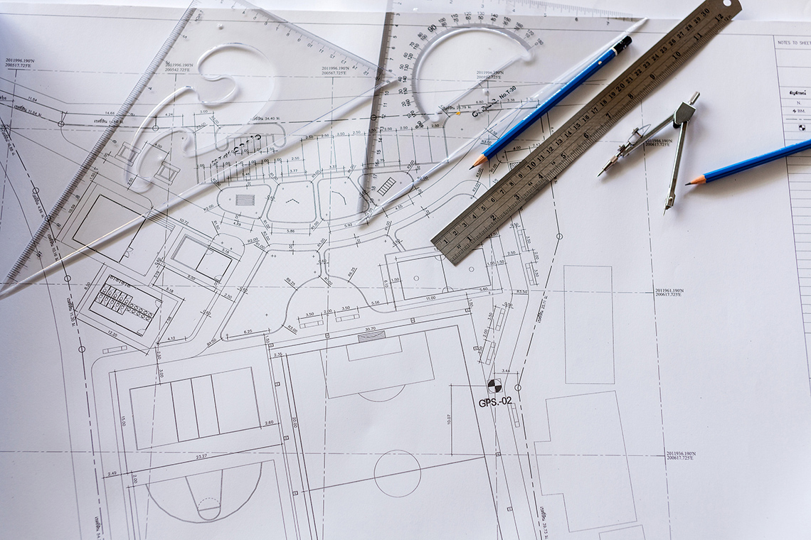 A blueprint with rules, and pencils on top.