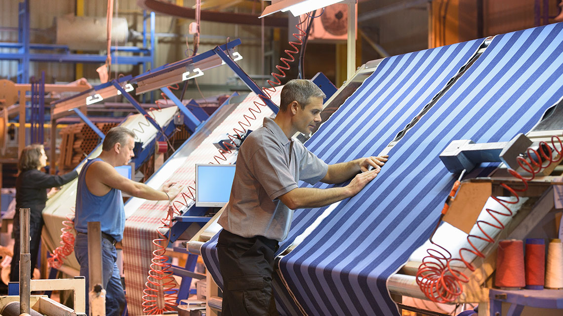 Several people measuring and cutting fabrics for specific designs