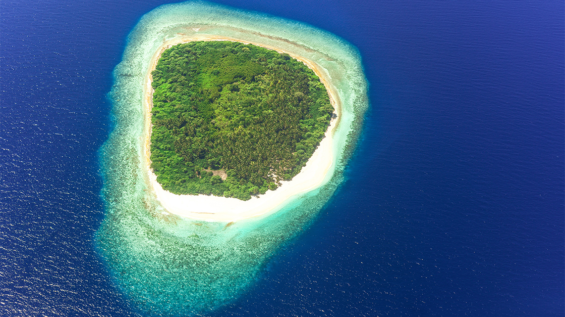 Round tropical island surrounded the ocean, with a sandy beach.