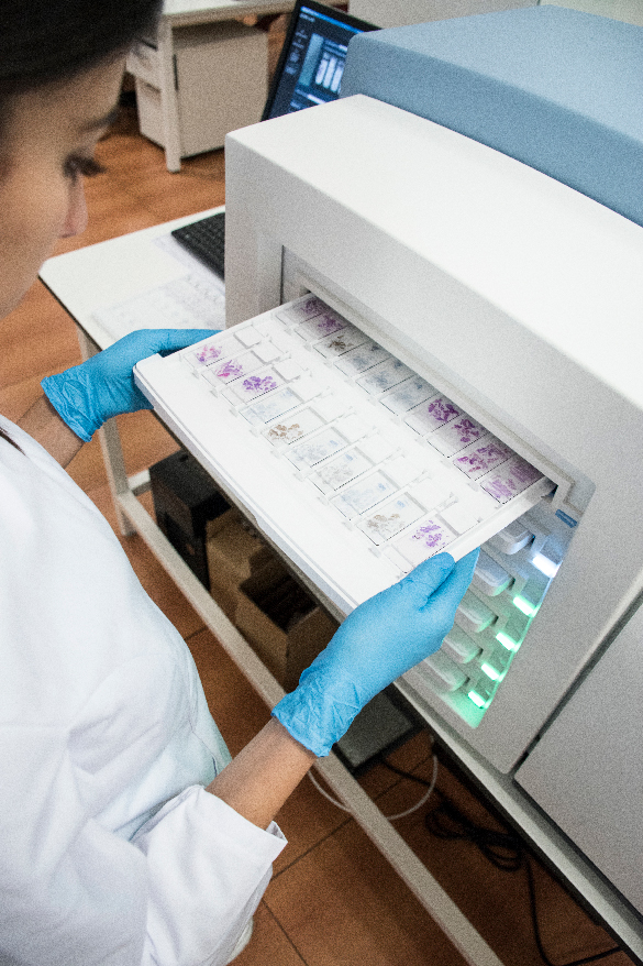 A person puts a tray of cell specimens into a cytology reader.