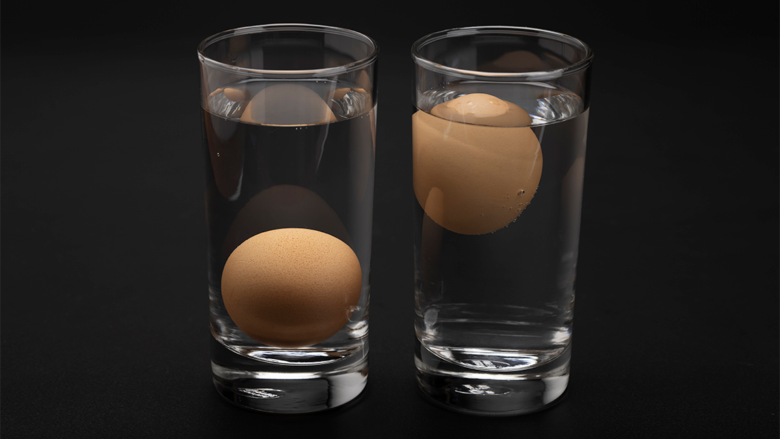 Two glasses with water, one with a sunken egg, the other with a floating egg