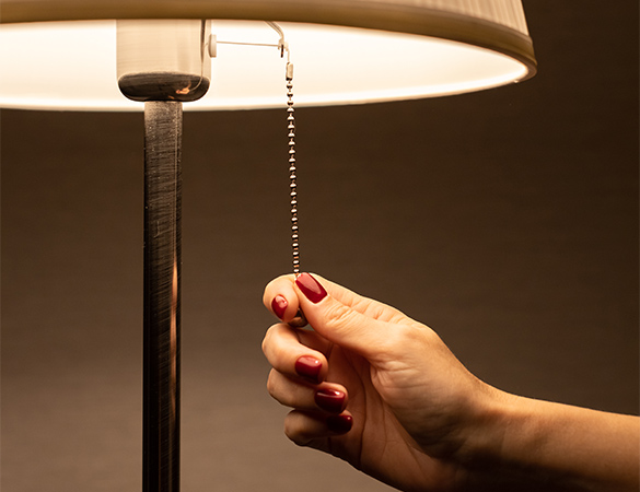 A hand reaching to turn off the lamp.
