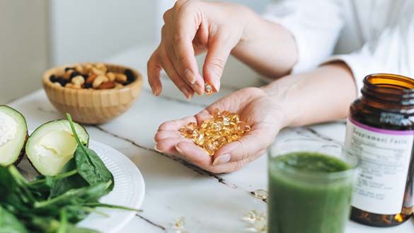 A person holding a large amount of vitamins in their hand.