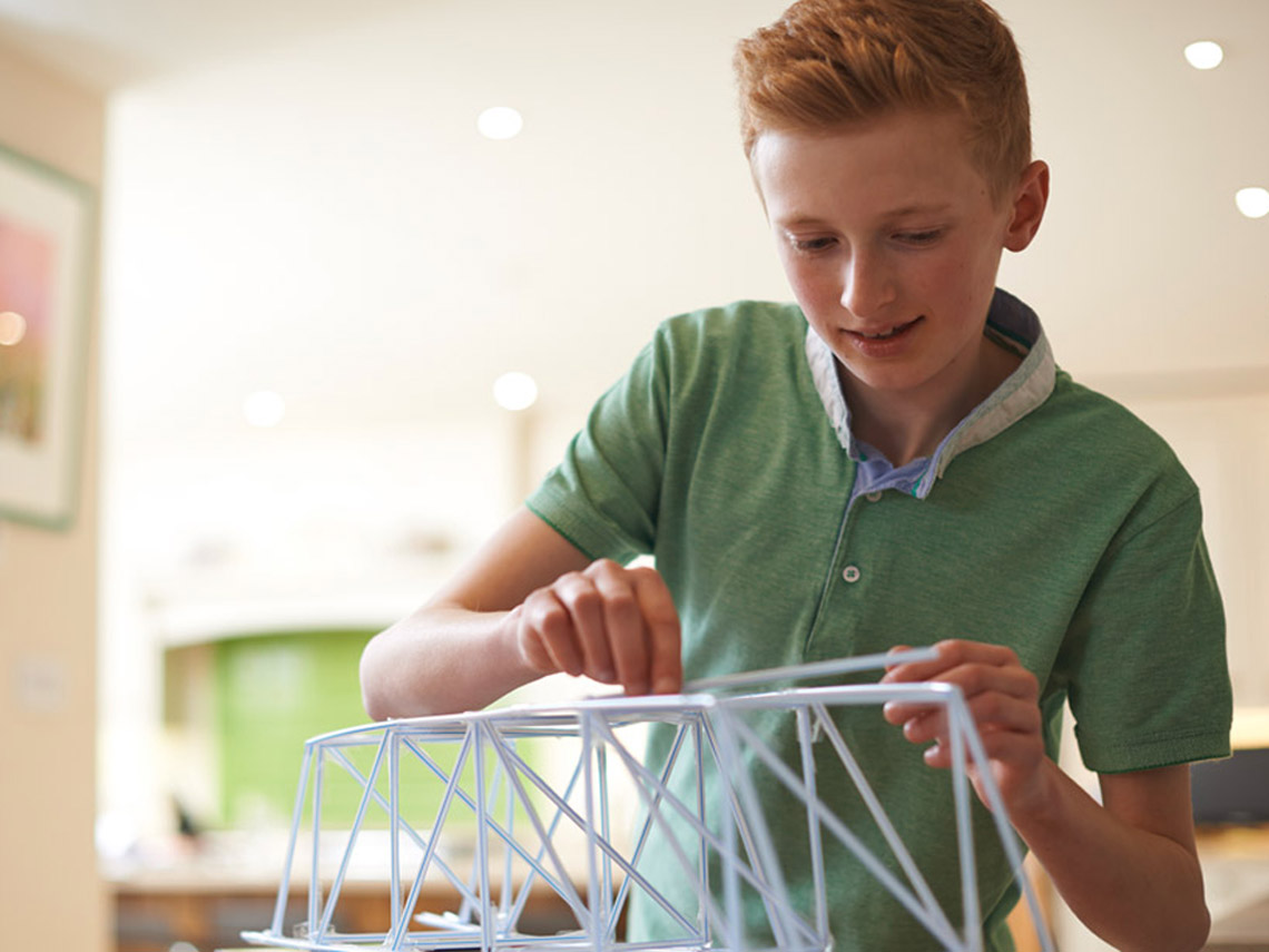 A child building a bridge using straws.