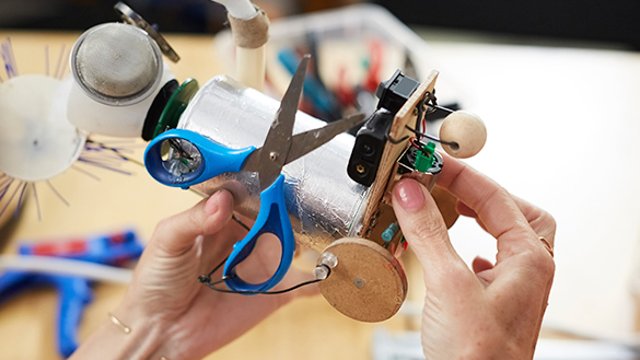 A person using mechanical devices to build a cart in science class.