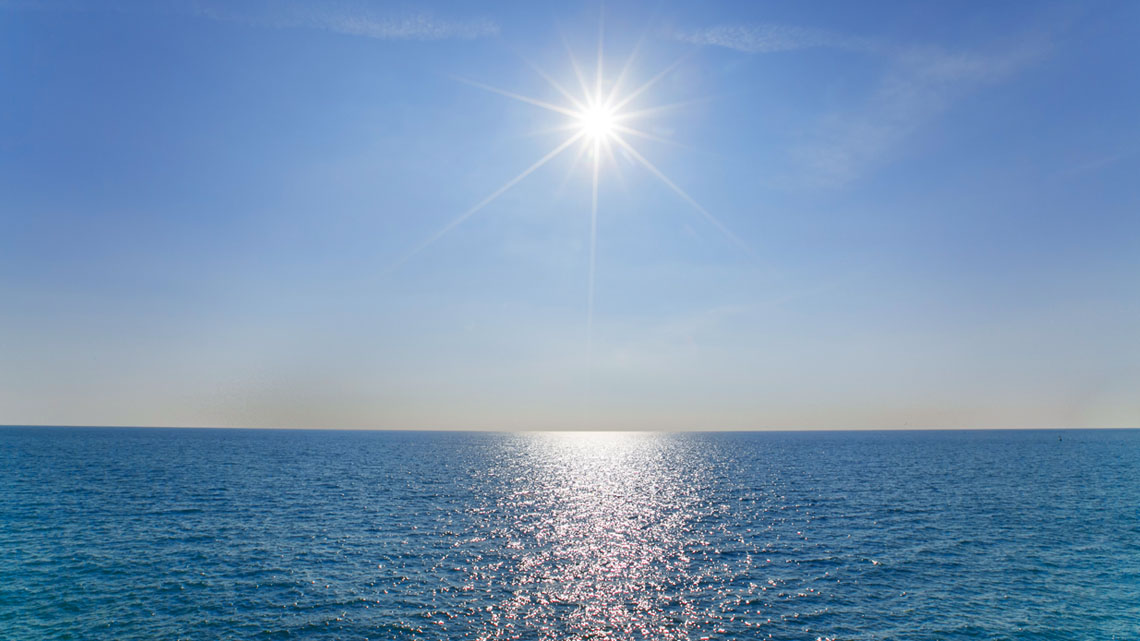 The sun shining over the water.