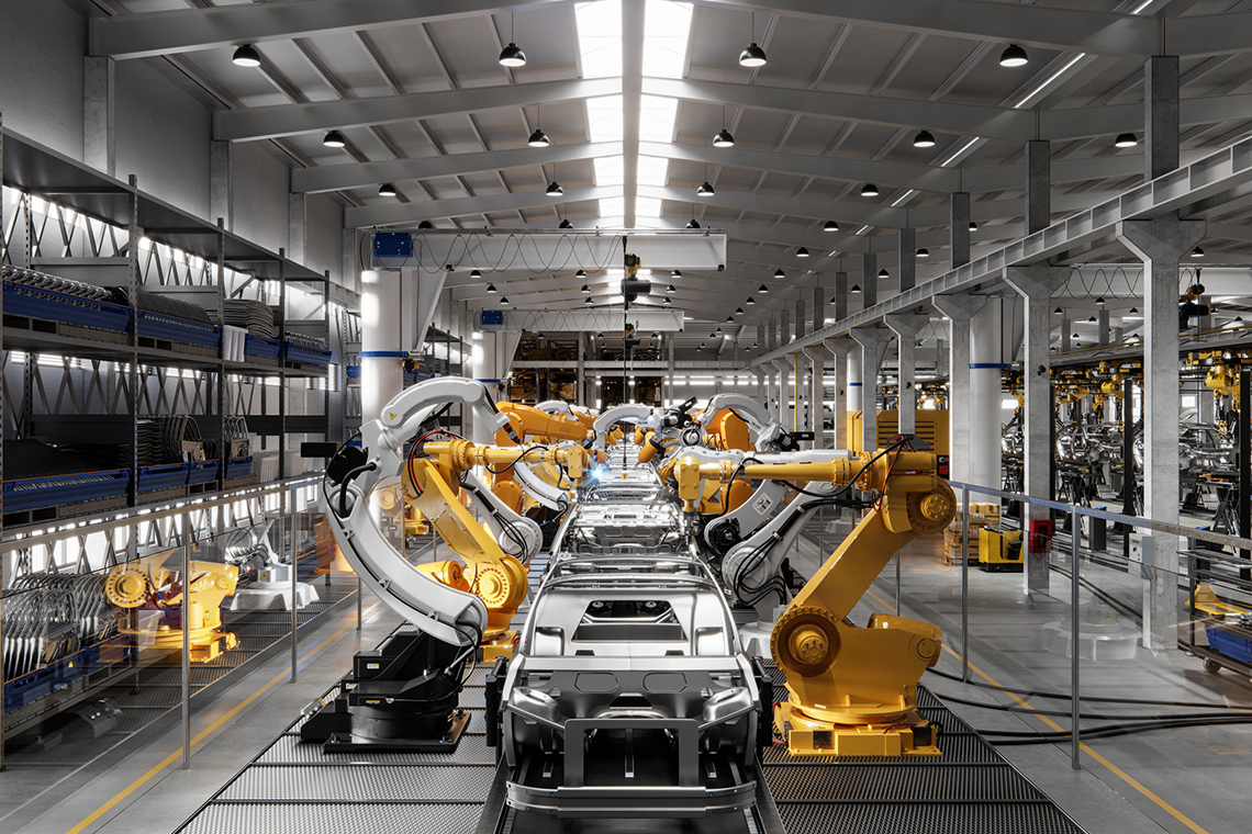 Image 1: A car being assembled with the use of automation. The silver frame of a car sits on a track while yellow robotic arms work on it.