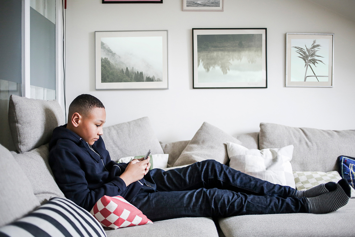 Image 3: Person holding their cell phone on a couch. They are potentially receiving auto-texts.