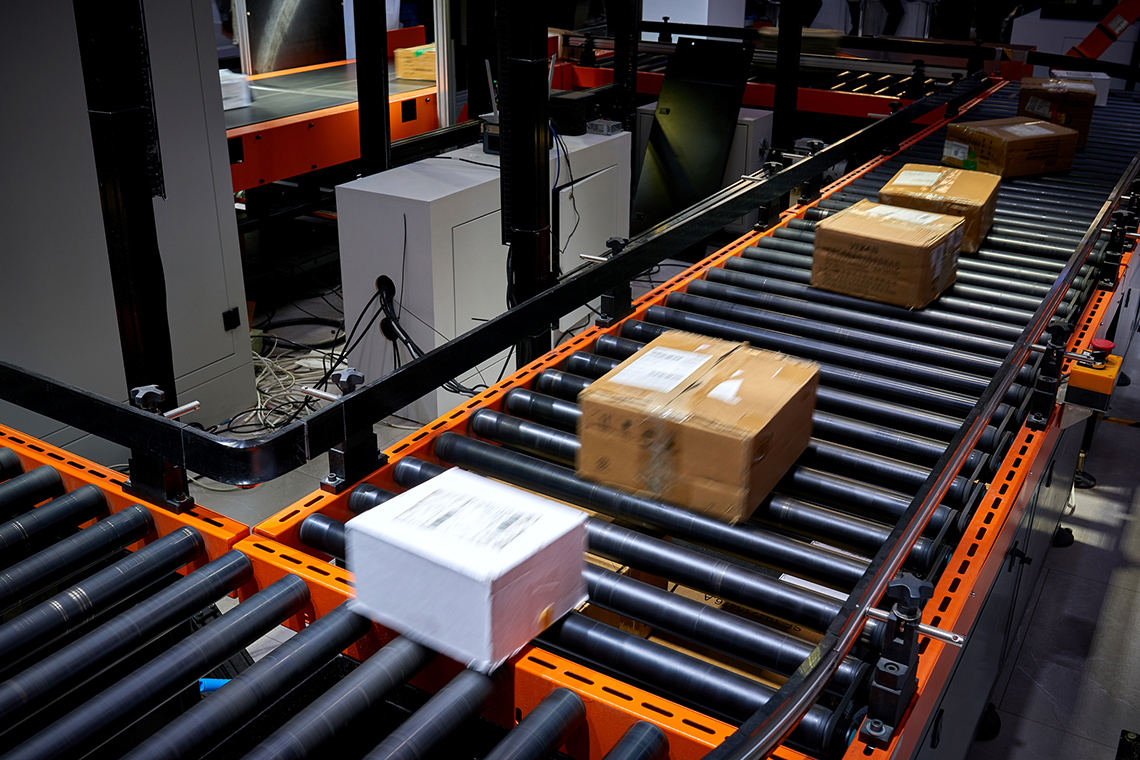 Image 4: Labelled boxes moving along a conveyor belt.