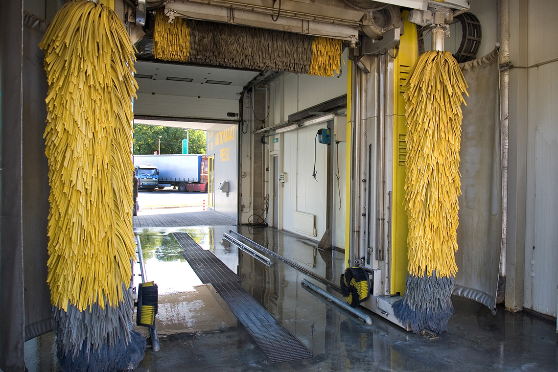 Image 5: Components of a car wash. The conveyor belt is on the floor while wipers line the walls.