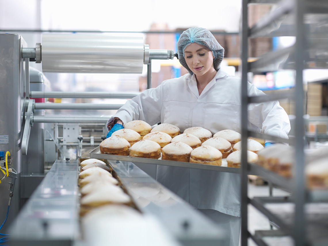 An assembly line of cakes being received by a person.