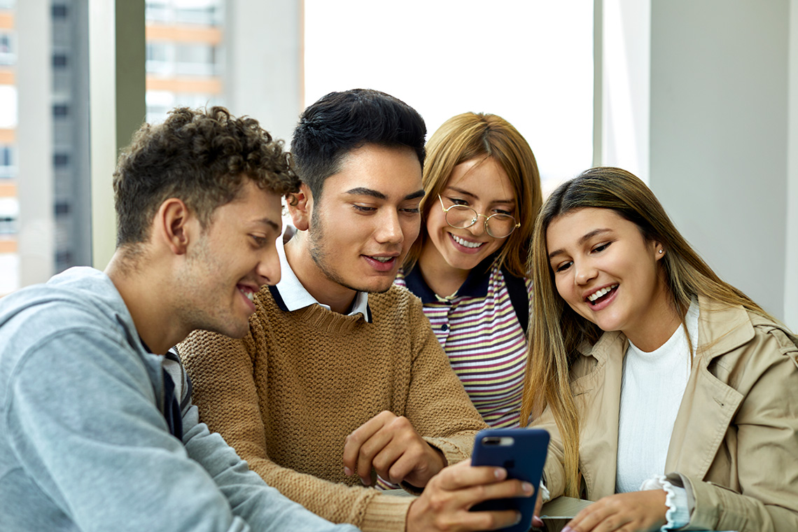 Four young people looking at a phone.