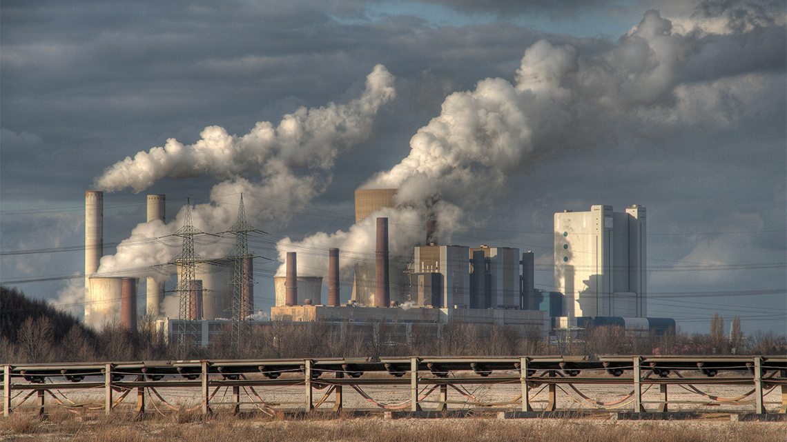 A large factory with many smokestacks releasing lots of dirty air into the atmosphere.