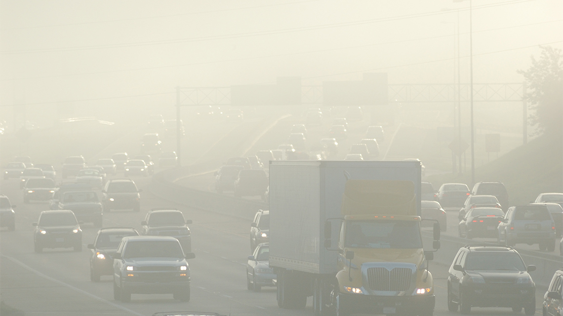 A road filled with traffic. The air is foggy due to all the car pollution.