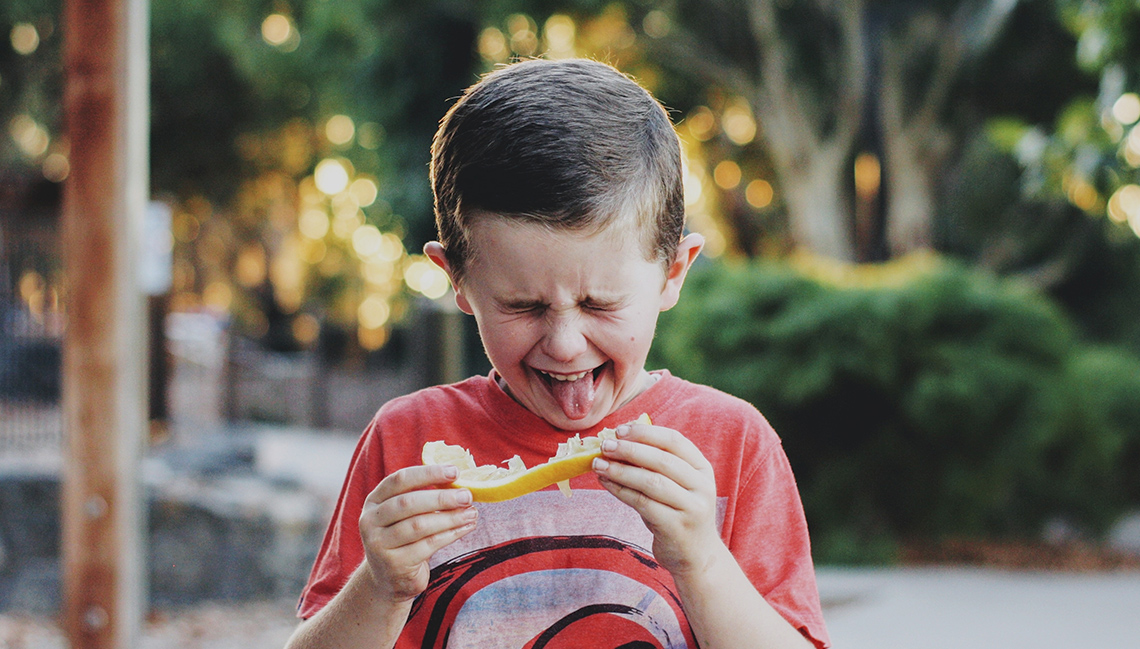 Child eating a lemon and making a face 
