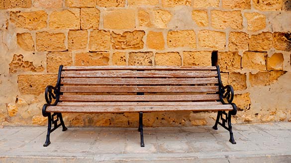 The bench is made of wood planks put together for the seat and the back but the arms and legs are made of metal.