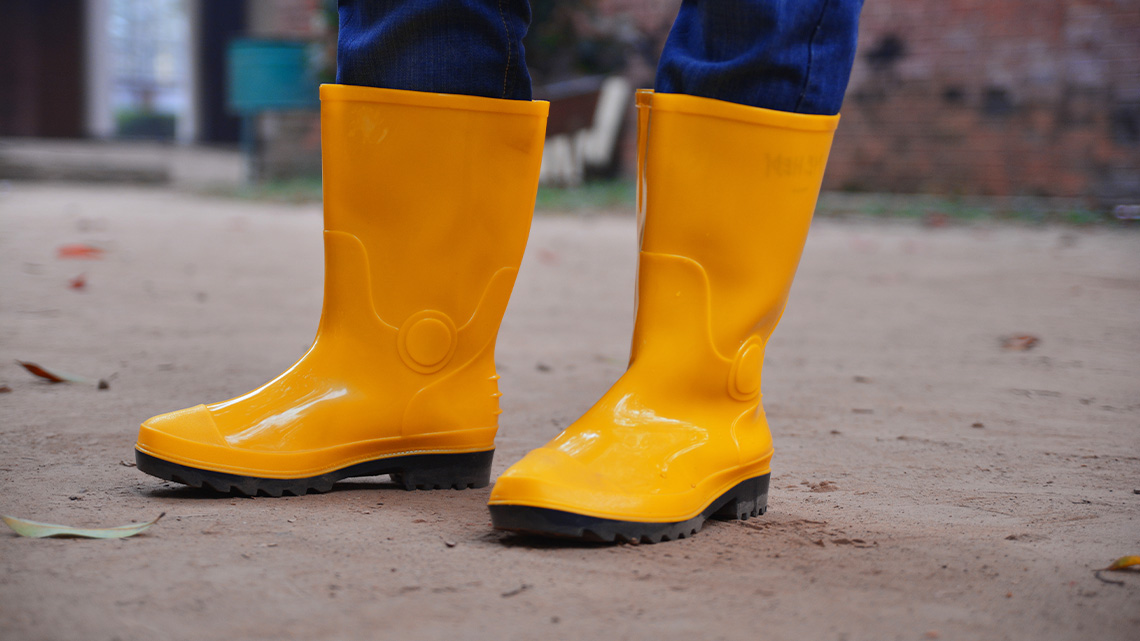 A close-up of a person wearing rubber boots.