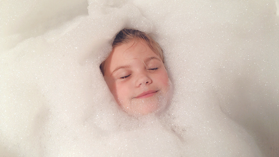 A learner laying in a bathtub surrounded by bubbles.