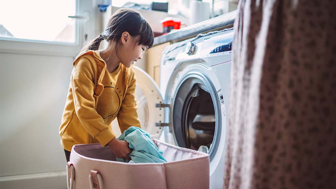 A learner is loading a washing machine with clothes.