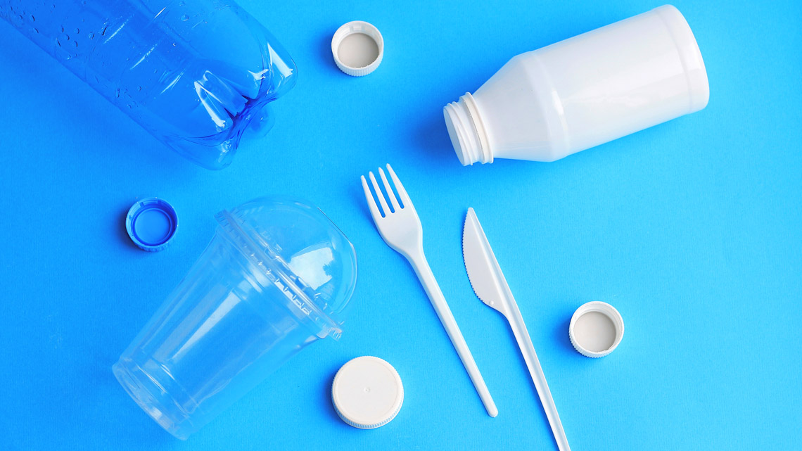 Single use plastics including a water bottle, drink containers, bottle lids, a fork and a knife.