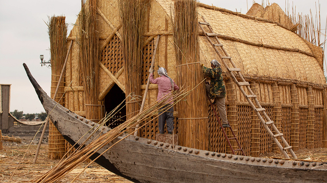 Iraqi builders and craftspeople constructing a structure from dried reeds.